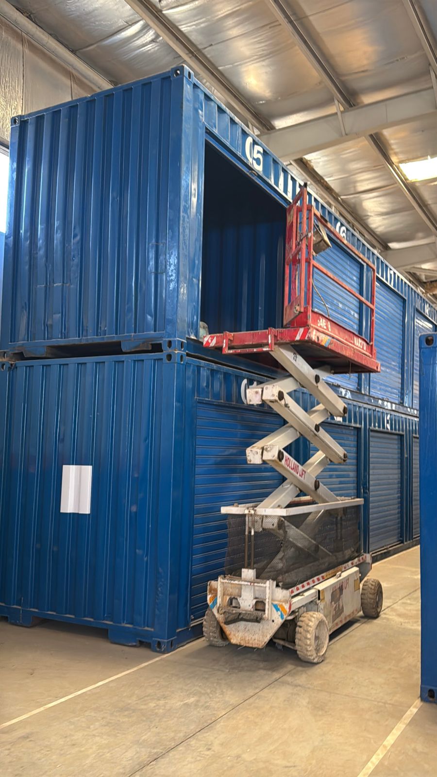 Scissor lift raised to reach an upper-level storage unit at Prime Spaces